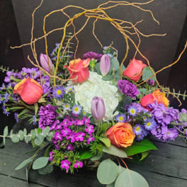 Colorful floral arrangement with roses, tulips, hydrangea, and purple filler flowers