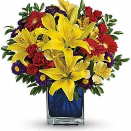 Bouquet of yellow lilies, red roses, and purple daisies in a blue glass vase