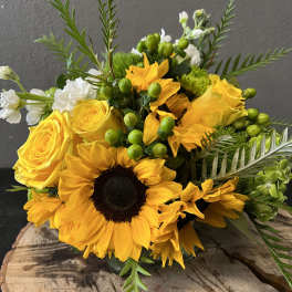 Yellow sunflowers and roses with green berries in a bouquet