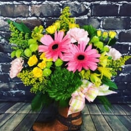 Bouquet of pink gerbera daisies and yellow flowers in a boot-shaped container