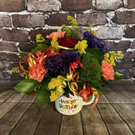 Colorful birthday flower arrangement in a mug-shaped container
