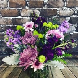 Purple and pink mixed bouquet in a green patterned vase