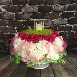 Round floral arrangement with pink roses and white blooms on a pedestal stand