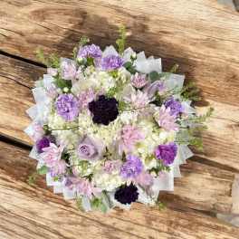 Lavender and white bouquet with carnations and hydrangeas wrapped in white paper