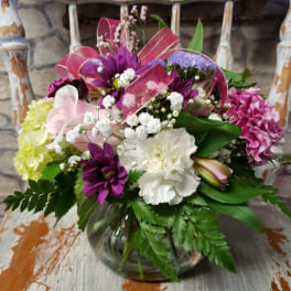 Mixed bouquet of purple, pink, white, and yellow flowers in a glass vase