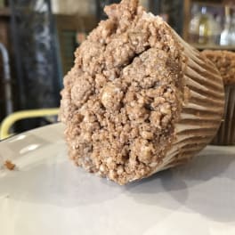 Two crumb-topped muffins on a white plate