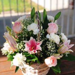 Basket arrangement of pink lilies, roses, and white carnations