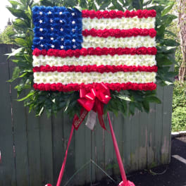 Floral standing tribute arranged like an American flag with red, white, and blue flowers