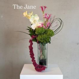 Tall floral arrangement in a clear glass vase with pink, white, and green blooms