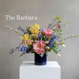 Colorful mixed bouquet in a dark vase on a white pedestal