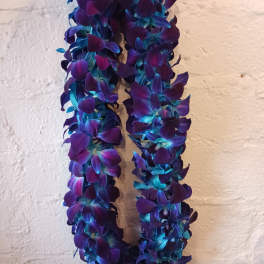 Two purple and blue flower leis hanging against a wall