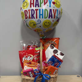 Birthday balloon above a basket of assorted candy