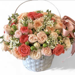 Basket of pink and peach roses with a ribbon handle