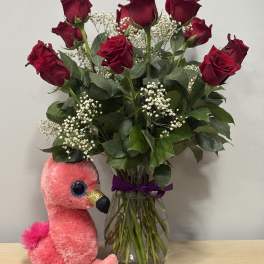 Red roses in a glass vase with a pink plush flamingo