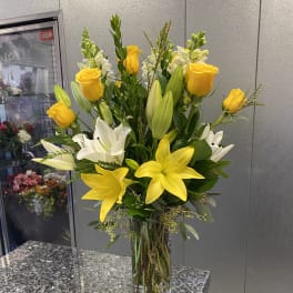Yellow roses and white lilies in a clear glass vase