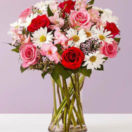 Bouquet of red and pink roses with white daisies in a glass vase
