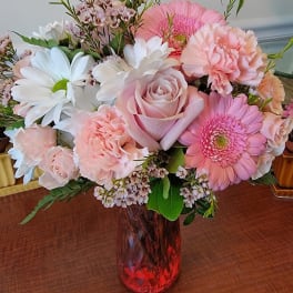 Pink and white mixed bouquet in a red glass vase