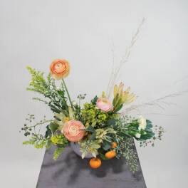 Low floral arrangement with peach blooms in a gray container