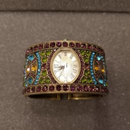 Jeweled wristwatch with a gold-toned face and multicolored stones
