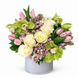 Bouquet of cream roses, pink tulips, and green orchids in a gray vase