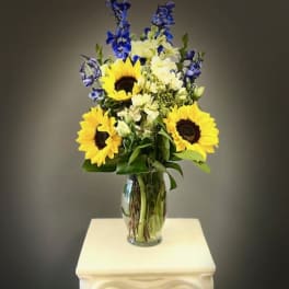 Sunflowers and blue flowers arranged in a clear glass vase