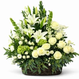 White lilies and roses arranged in a wicker basket