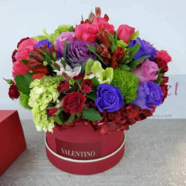 Colorful bouquet of roses and mixed flowers in a red round box