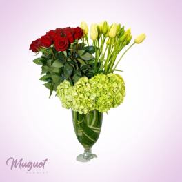 Red roses and yellow tulips in a glass vase with green hydrangeas