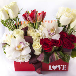 Red and white roses with orchids in a red box marked LOVE