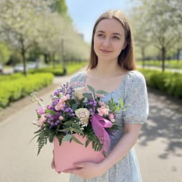 Woman holding a pink box of mixed pink and purple flowers