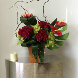 Red roses and red anthuriums arranged in a wooden vase