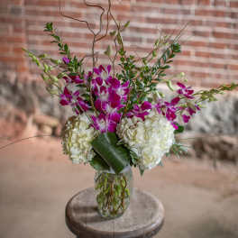 Tall vase arrangement with purple orchids and white hydrangeas
