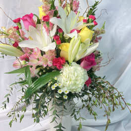 Tall mixed bouquet in a white vase with lilies, roses, and pink blooms