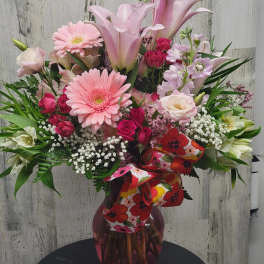 Pink mixed bouquet in a glass vase with a floral ribbon