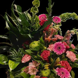 Mixed bouquet with pink gerberas, red roses, and green blooms