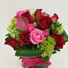 Bouquet of red and pink roses with green hydrangeas in a glass vase