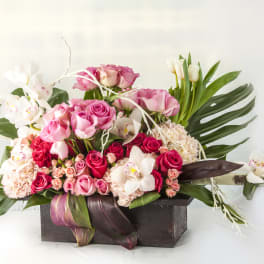 Pink roses and white orchids arranged in a dark wooden box