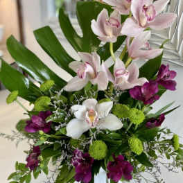 Arrangement of pink and white orchids with green button mums in a vase