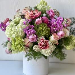 Mixed pink and green floral arrangement in a white vase