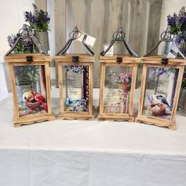 Four wooden lanterns with floral prints and small purple flower arrangements
