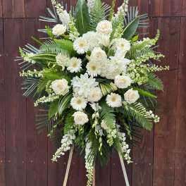 White floral standing spray with roses and lilies on an easel