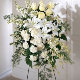Standing floral spray with white lilies, yellow roses, and white carnations