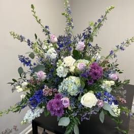 Large mixed floral arrangement with roses, hydrangeas, and purple blooms