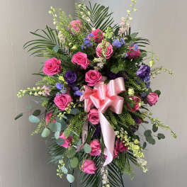 Standing floral spray with pink roses and purple blooms on an easel