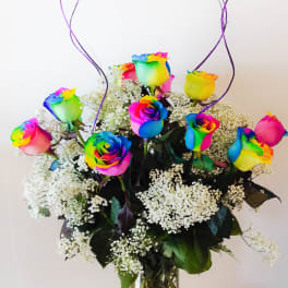 Rainbow-colored roses in a glass vase with white baby's breath