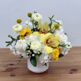 White and yellow floral arrangement in a white vase