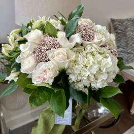 Bouquet of white roses, hydrangeas, and pale pink berries with green leaves