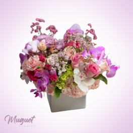 Pink and purple floral arrangement in a gray square vase