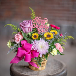 Basket arrangement with pink and purple flowers and a Happy Mother's Day pick