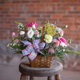 Basket arrangement of pink and white flowers with a Mother's Day pick
